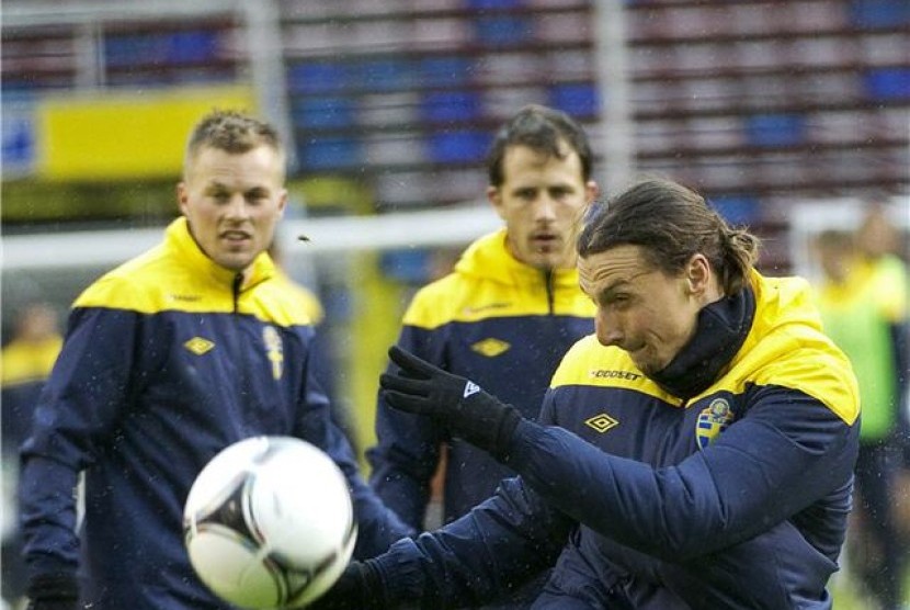 Tobias Hysen (tengah) dan Sebastian Larsson (kiri) menyaksikan striker andalan Swedia, Zlatan Ibrahimovic, melepaskan tendangan dalam sesi latihan di Stadion Rasunda, Stockholm, Sweden, pada pekan lalu. 