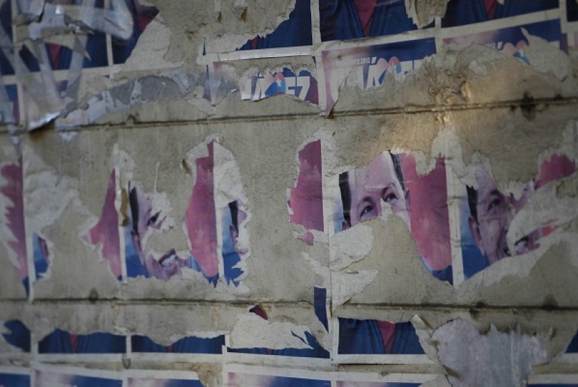    Torn posters of Venezuela's late President Hugo Chavez are seen on a wall along a street in Caracas, March 9, 2013. 