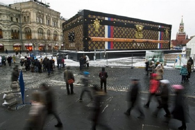 Tourists and visitors pass by a two-story Louis Vuitton suitcase erected at the Red Square in Moscow, Russia, Wednesday, Nov. 27, 2013.