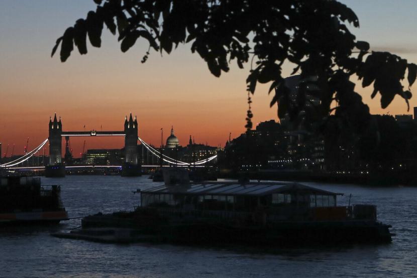 Tower Bridge dan kubah Katedral St. Paul bermandikan cahaya matahari terbenam di London, Selasa 21 Juni 2022.