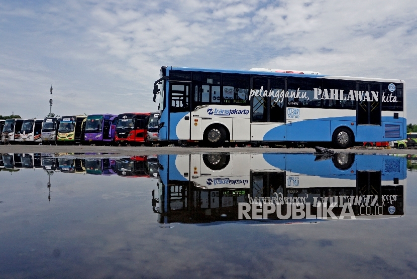  Transjakarta melintas di depan bus AKAP yang terparkir di Terminal Terpadu Pulo Gebang, Jakarta, Selasa (3/1).