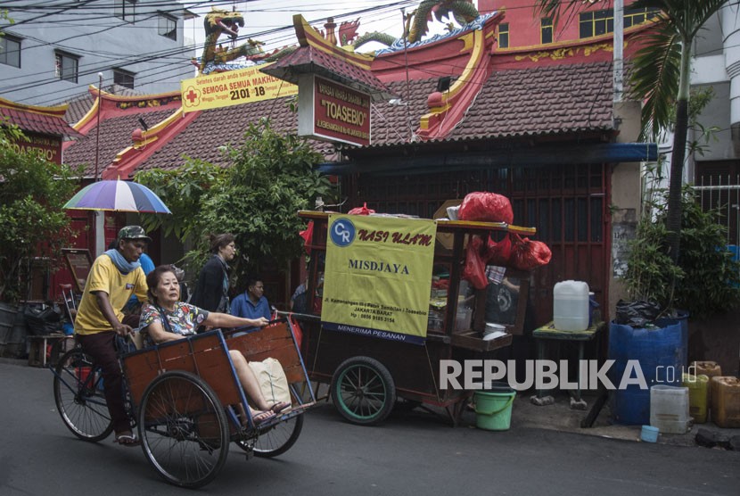 Tukang becak mengangkut penumpang saat melintas di kawasan Petak Sembilan, Glodok, Jakarta, Selasa (16/1).