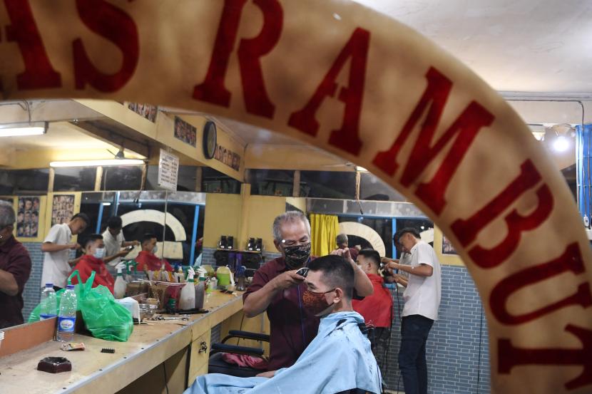 Tukang cukur memangkas rambut pelanggannya di salah satu barbershop di Jakarta, Rabu (24/3/2021). Pemerintah akan melanjutkan program Pemulihan Ekonomi Nasional (PEN) bagi Koperasi Usaha Mikro, Kecil, dan Menengah (KUMKM) pada 2021 yang terdiri dari fasilitas subsidi bunga KUR dan pembiayaan modal kerja koperasi serta bantuan produktif usaha mikro atau (BLT UMKM).