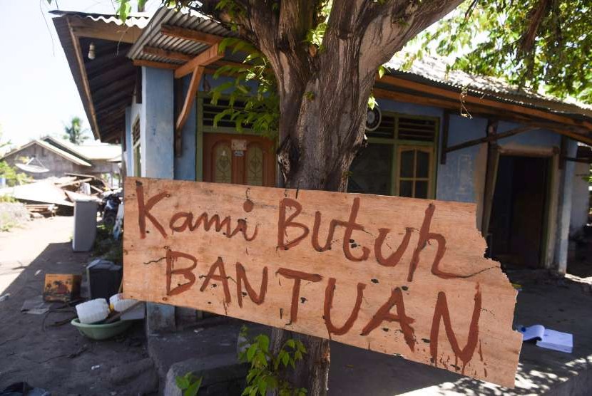 Tulisan pengungsi korban gempa bumi dipasang di sebuah pohon di sekitar lokasi tempat pengungsian darurat di Kayangan, Lombok Utara, NTB, Minggu (12/8).
