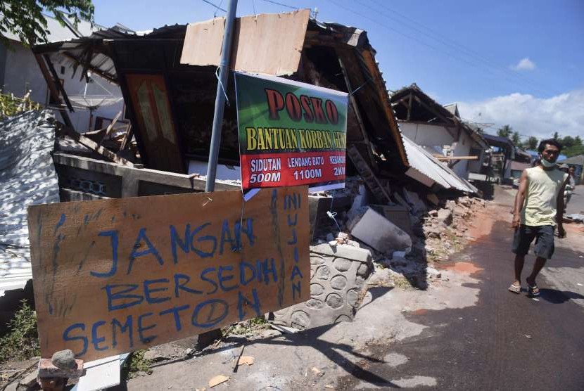 Tulisan pengungsi korban gempa bumi dipasang di sebuah potongan kayu di sekitar lokasi tempat pengungsian darurat di Kayangan, Lombok Utara, NTB, Minggu (12/8). 