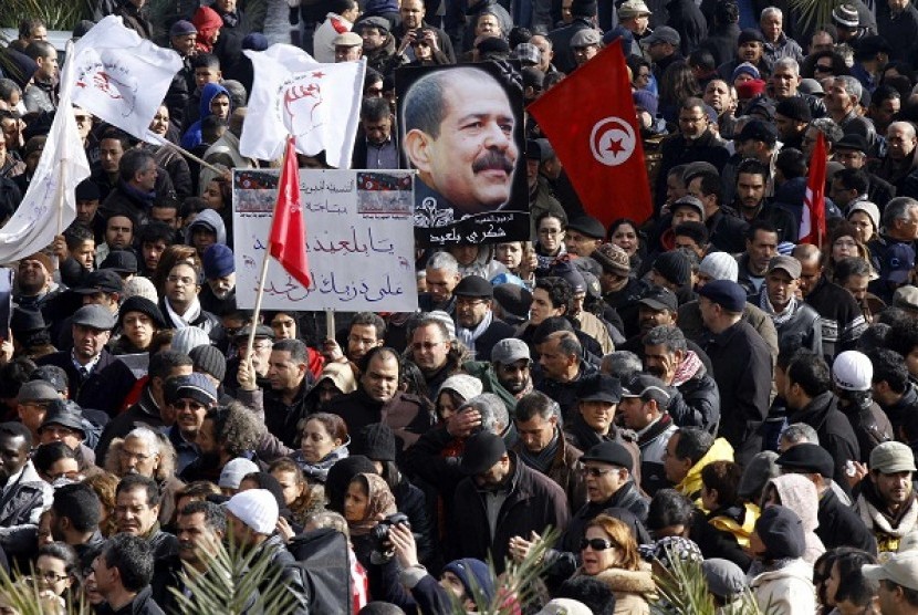 TDemonstran Tunisia memegang spanduk dengan gambar tokoh oposisi Chokri Belaid, dalam pemakaman di distrik Jabal Jelloud, Tunis, 8 Februari 2013.