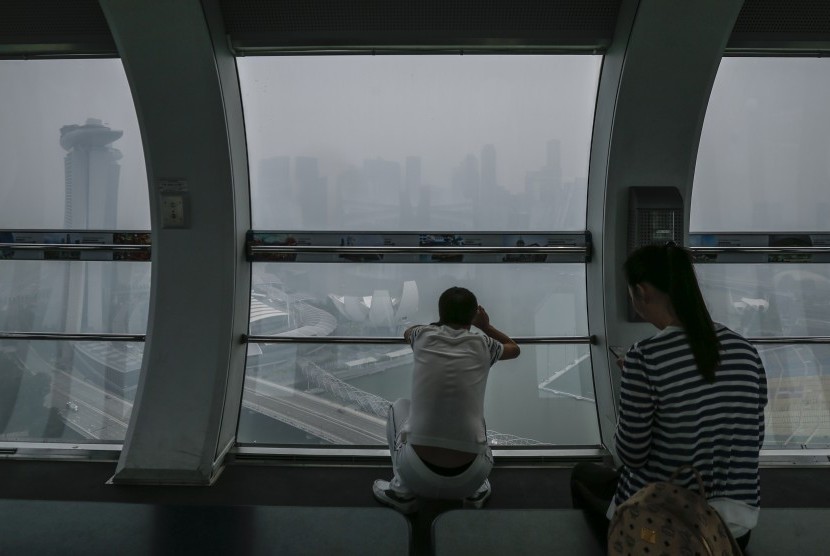 Turis asal Cina melihat pemandangan Singapura yang tertutup kabut asap dari salah satu kabin Singapore Flyer (23/10).