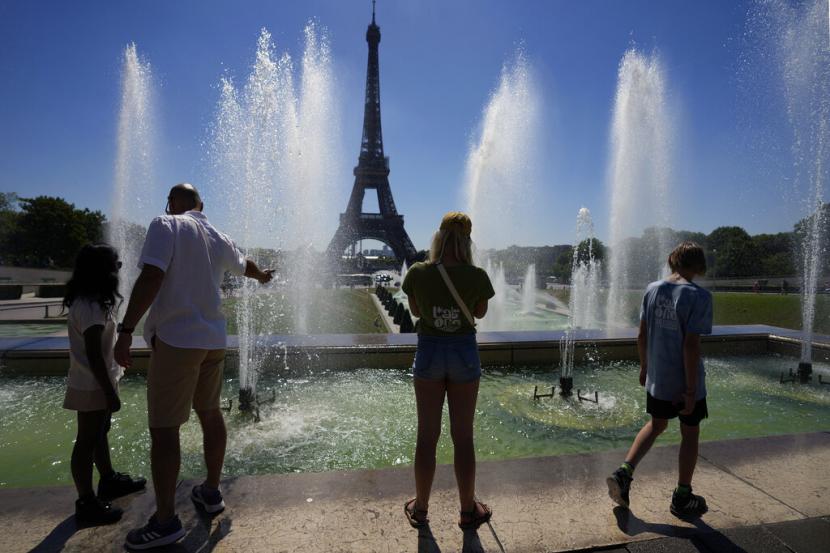 Turis berdiri di dekat Air Mancur Trocadero di sebelah Menara Eiffel, saat Eropa berada di bawah gelombang panas yang luar biasa ekstrem, di Paris, Prancis, Rabu, 3 Agustus 2022. Otoritas regional Paris memperingatkan warga untuk waspada Rabu, dengan suhu melonjak hingga 36 derajat Celcius (97 Fahrenheit).
