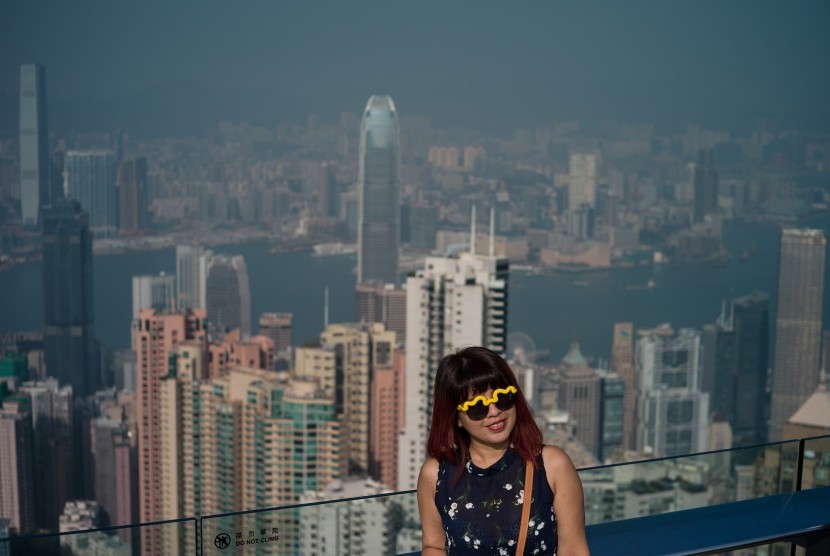 Turis berfoto dengan latar belakangan Kota Hong Kong.