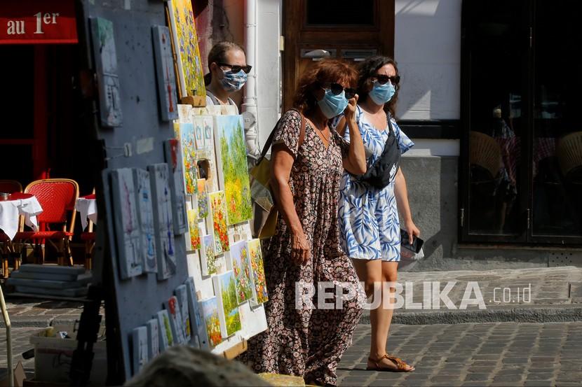 Turis berjalan-jalan dengan mengenakan masker di distrik Montmartre di Paris, Senin (10/8/2020). 