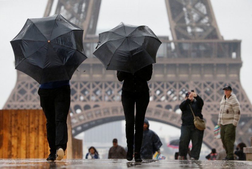 Turis berjalan-jalan sambil memakai payung di pelantaran Trocadero di depan Menara Eiffel saat hujan mengguyur Paris, Prancis, pada 30 Mei 2016. 
