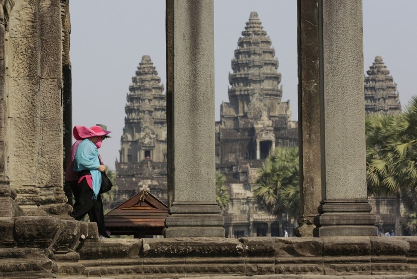 Turis melewati kuil Angkor Wat di Kamboja.