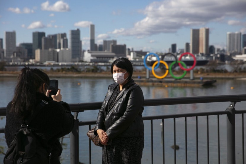 Turis mengenakan masker berfoto dengan latar logo Olimpiade di Odaiba, Tokyo, Jepang, Rabu (29/1). Olimpiade Tokyo terancam batal akibat virus corona yang kian meluas.