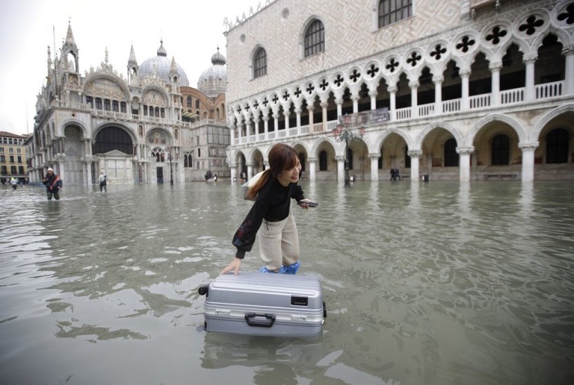 Turis menggeret kopernya di St Mark Square, Venesia, Rabu (13/11). Banjir setinggi 187 cm melanda sebagian besar Venesia.