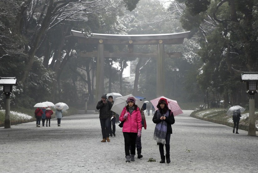Turis mengunjungi Kuil Meji yang tertutup salju di Tokyo, Jepang.