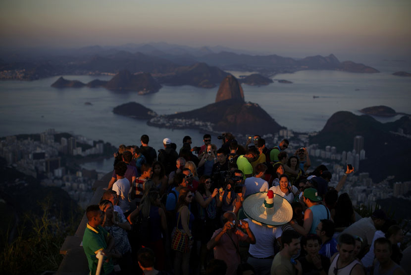 Turis menikmati matahari terbenam di puncak Gunung Corcovado, Rio de Janeiro, Brasil. 