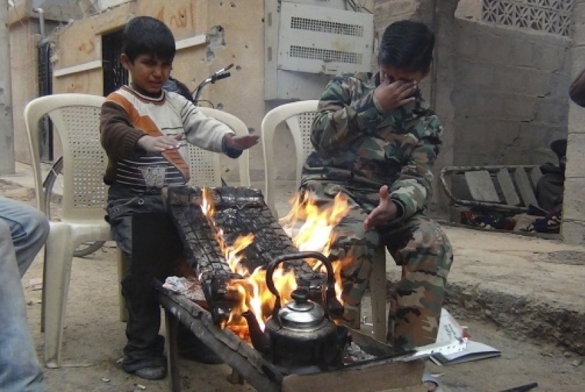 Two boys warm themselves around a fire in Deir Al-Zor, in this picture provided by Shaam News Network and taken January 8, 2013. Picture taken January 8, 2013.
