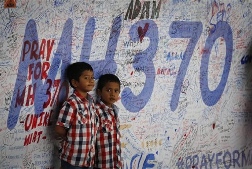Dua anak Malaysia berdiri di depan papan permohonan agar penumpang Malaysia Airlines MH370 ditemukan di Sepang, Malaysia.