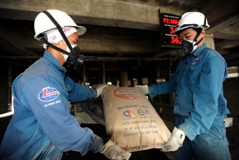 Two workers unload a sack of cement produced by Thang Long Cement plant in Hoanh Bo, Vietnam. PT Semen Gresik has acquire 70 percent shares of Thang Long Cement. Now Sement Gresik rebrands to Semen Indonesia. (illustration)   