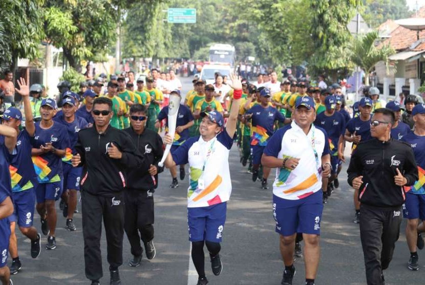 Udjo (kiri) membawa obor Asian Games 2018 saat Torch Relay Asian Games 2018 di Purwakarta, Jumat (10/8).