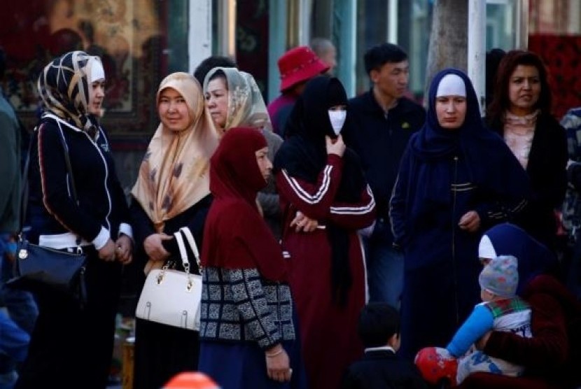 Uighur women stand next to a street to wait for a bus in downtown Urumqi, Xinjiang Uighur Autonomous Region May 1, 2014.