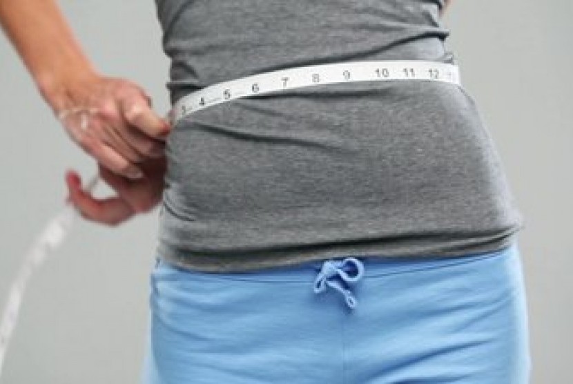 Pria mengukur lingkar pinggangnya (ilustrasi). Indeks massa tubuh dihitung dengan membagi berat badan seseorang dengan kuadrat tinggi badannya.