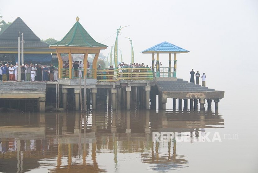 Muslims perform Eid al-Adha prayers on the banks of the Kapuas River in Pontianak, West Kalimantan, Sunday. Muslims in Pontianak perform Eid al-Adha prayers in a condition shrouded in thick haze from forest and land fires.