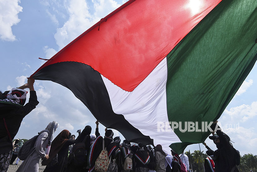 Umat Islam mengibarkan bendera Palestina saat mengikuti aksi 115 di kawasan Monas, Jakarta, Jumat (11/5).