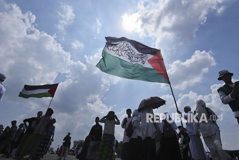 Umat Islam mengibarkan bendera Palestina saat mengikuti aksi 115 di kawasan Monas, Jakarta, Jumat (11/5).