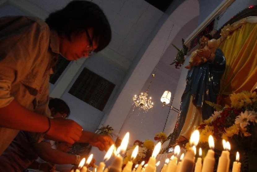 Umat Kristiani menyalakan lilin saat misa natal. ilustrasi