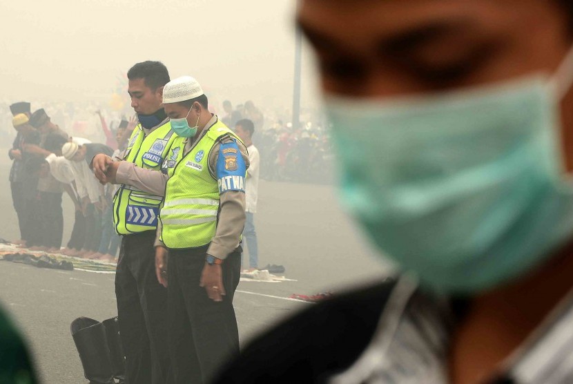 Umat muslim di kota Palembang melaksanakan salat Idul Adha mengenakan masker di Bundaran Air Mancur Masjid Agung SMB II yang diselimuti kabut asap, Palembang, Sumatera Selatan, Kamis (24/9).