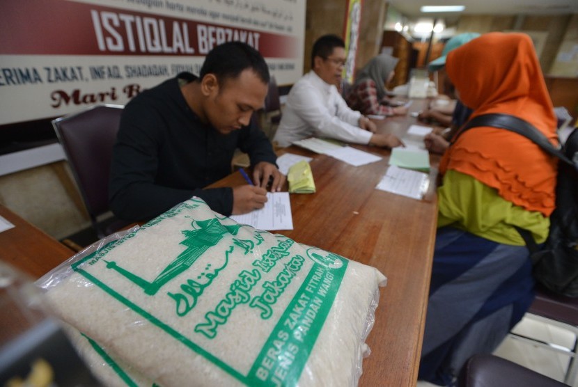 Umat muslim membayarkan zakat fitrah kepada panitia amil zakat di Masjid Istiqlal, Jakarta, Senin (11/6).
