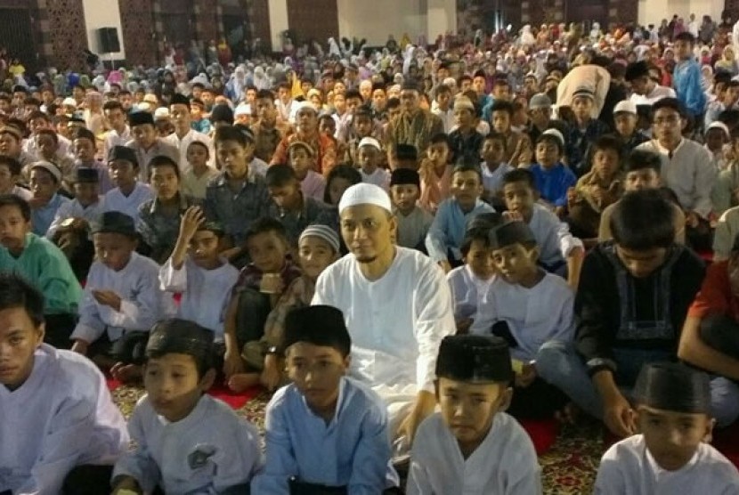Ustad Muhammad Arifin Ilham duduk bersama anak anak yatim piatu di mesjid Raya Sumatra Barat.