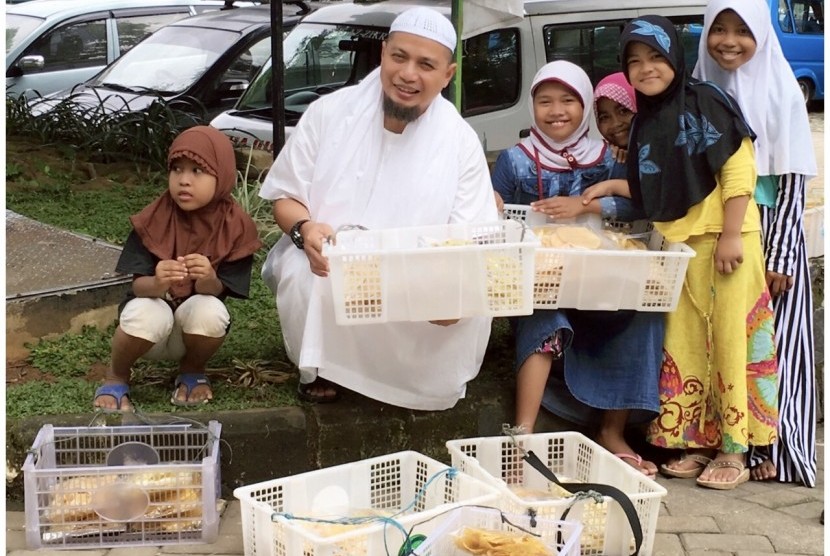 Ustaz Arifin Ilham turut membantu para pedagang cilik menjajakan keripik dan rengginang di depan Masjid Az-Zikra Sentul, Bogor, Jawa Barat.