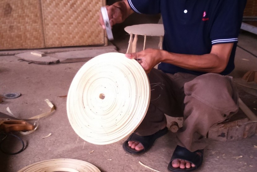 Utang, pengrajin bambu dari Selaawi Garut sedang membuat rumah lampu berukuran kecil.