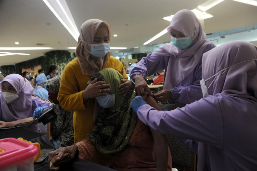 Vaksinator dan pengantar lansia membantu proses penyuntikan vaksin salah satu peserta pada gebyar vaksin lansia di Palembang Indah Mall, Sumsel, Sabtu (29/5/2021). Kegiatan vaksin dalam rangka hari lanjut usia nasional ini menargetkan 200 lansia penerima vaksin dengan sistem satu pegawai mal membawa dua lansia untuk divaksinasi.