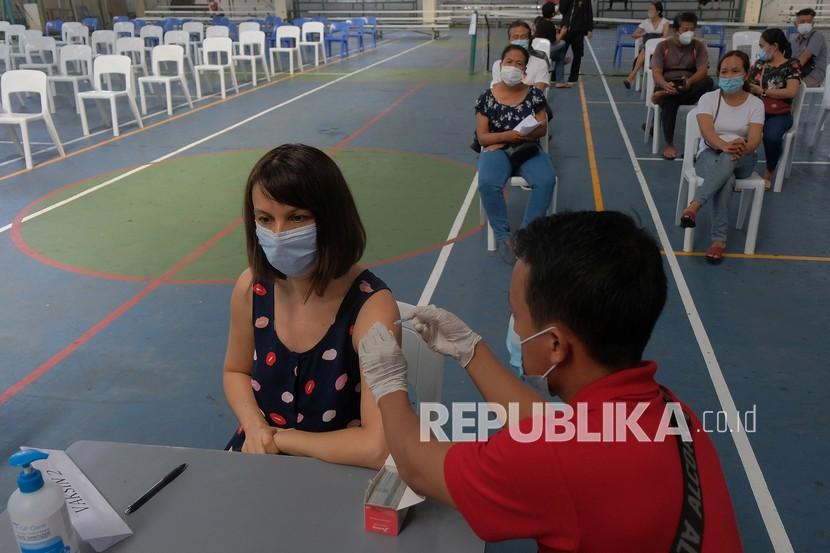 Vaksinator menyuntikan vaksin COVID-19 kepada seorang Warga Negara Asing (WNA) saat vaksinasi massal Menuju Sanur Zona Hijau di Bali International School, Sanur, Denpasar, Bali, Selasa (30/3/2021). Pemerintah Kota Denpasar mendata vaksinasi COVID-19 di wilayah Sanur pada Senin (29/3) tersebut telah diikuti 156 WNA yang menetap di kawasan itu dengan persyaratan memiliki Kartu Izin Tinggal Tetap (KITAP), Kartu Izin Tinggal Terbatas (KITAS) dan Kartu Tanda Penduduk (KTP). 