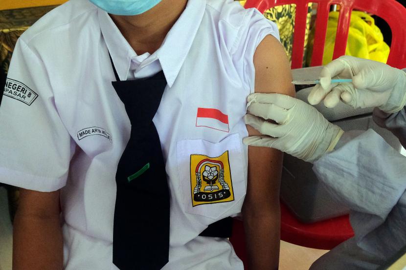 Vaksinasi menjadi salah satu faktor penentu pembelajaran tatap muka bisa digelar. Foto: Vaksinator menyuntikkan vaksin Sinovac dengan takaran 0,5 ml per dosis kepada seorang siswa SMP saat pencanangan dimulainya vaksinasi COVID-19 untuk anak usia 12 - 17 tahun di SMP Negeri 8 Denpasar, Bali, Senin (5/7/2021).