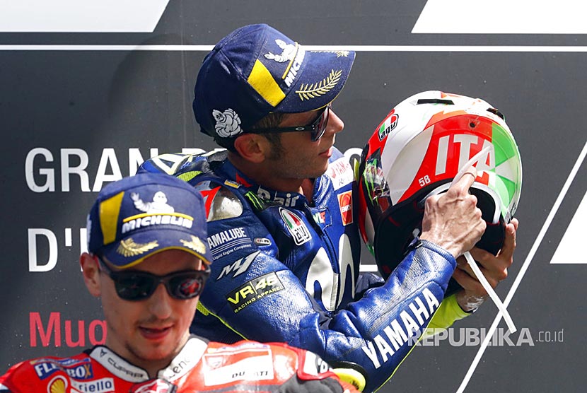 Valentino Rossi menunjukkan helmnnya yang bertuliskan 'Italia' di Mugello Circuit, Ahad (3/6).