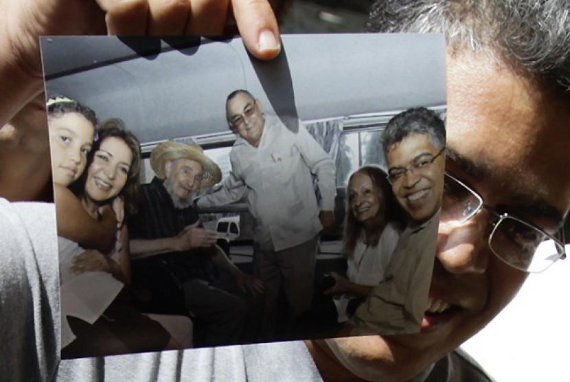 Venezuela's former vice president Elias Jaua shows a picture of himself and former Cuban leader Fidel Castro, (3rd from left), in Havana October 21, 2012. Man in centre of the picture is Hotel Nacional Director Antonio Martinez and woman second from right is Castro's wife Dalia Soto.