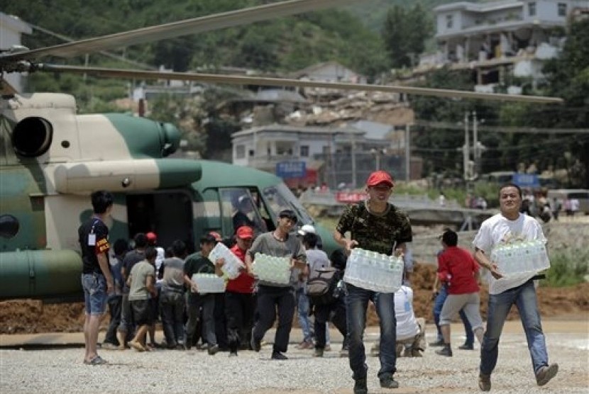 Volunteers deliver bottles of water transported by a helicopter to the earthquake-hit Longtoushan town in Lucian county in southwest China's Yunnan province Wednesday, Aug. 6, 2014. 