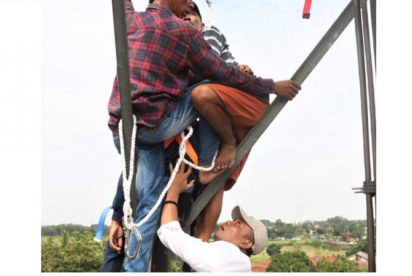 Wakil Bupati Purwakarta, Aming (kemeja putih dan topi) saat membantu evakuasi warganya yang hendak melakukan percobaan bunuh diri dengan memanjat tower telekomunikasi di Kampung Cikuda, Desa Karyamekar, Kecamatan Cibatu, Selasa (12/3).