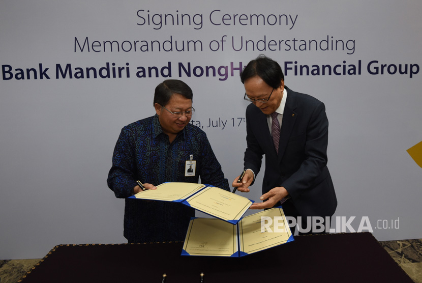 Wakil Direktur Utama Bank Mandiri Sulaiman A Arianto (kiri) dan Chairman & CEO NongHyup Financial Kim Yong Hwan bertukar lembar nota kesepahaman saat penandatangan kerjasama sejumlah bisnis perbankan di Plaza Mandiri, Jakarta (17/7).