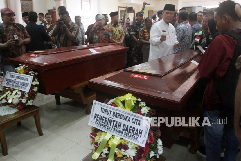 Wakil Gubernur Sumatera Barat Nasrul Abit (kanan) berdiri di antara dua peti jenazah korban kerusuhan Wamena yang telah tiba di Bandara International Minangkabau (BIM), Kabupaten Padang Pariaman, Sumatera Barat, Kamis (26/9/2019).