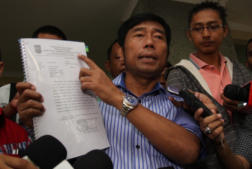 Wakil Ketua DPRD DKI Jakarta Abraham Lunggana alias Haji Lulung (kanan) menunjukkan surat hasil evaluasi anggaran perubahan daerah dari Kemendagri kepada wartawan saat tiba di Bareskrim Mabes Polri, Jakarta, Kamis (25/2).