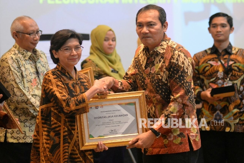 Wakil Ketua KPK Saut Situmorang memberikan pengahargaan kepada Deputi Komisioner OJK Bidang Audit Internal Sri R.A Faisal saat peringatan Hari Anti Korupsi Internasional (HAKI) 2016 di Pekanbaru, Riau, Jumat (9/12).