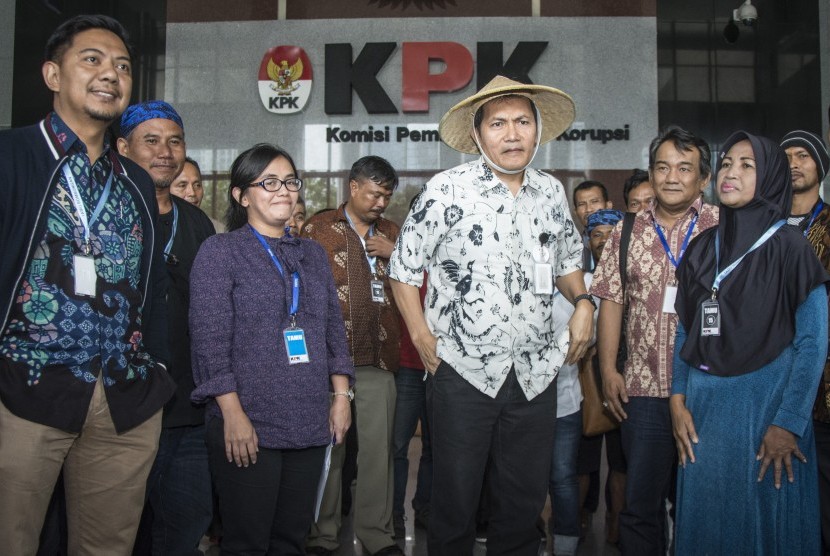 Wakil Ketua KPK Saut Situmorang (tengah) mengenakan caping yang diterima dari perwakilan Serikat Petani Pasundan di gedung KPK, Jakarta, Kamis (05/10). Sejumlah petani dari berbagai daerah yang tergabung dalam Komite Nasional Pembaruan Agraria (KNPA) memberikan dukungan kepada Komisi Pemberantasan Korupsi (KPK) untuk mengusut tuntas dan menindaklanjuti potensi korupsi yang sedang dan akan berlangsung di sektor agraria. 