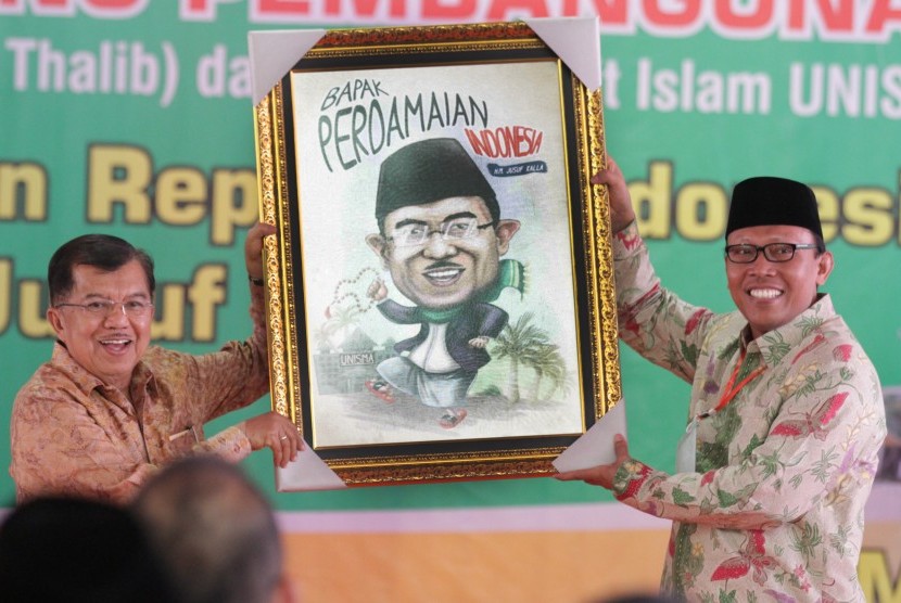 Wakil Presiden Jusuf Kalla (kiri) menerima lukisan karikatur dari Rektor Unisma, Maskuri (kanan) saat pemberian gelar Bapak Perdamaian di Universitas Islam Malang, Jawa Timur, Sabtu (31/10). 
