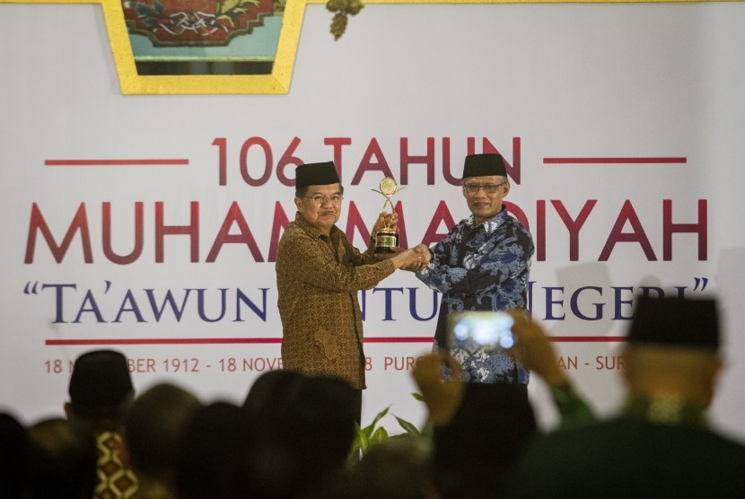 Wakil Presiden Jusuf Kalla (kiri) menerima penghargaan Muhammadiyah Award dari Ketua Umum PP Muhammadiyah Haedar Nashir (kanan) pada acara Milad Muhammadiyah ke-106 di Pura Mangkunegaran, Solo, Jawa Tengah, Ahad (18/11).
