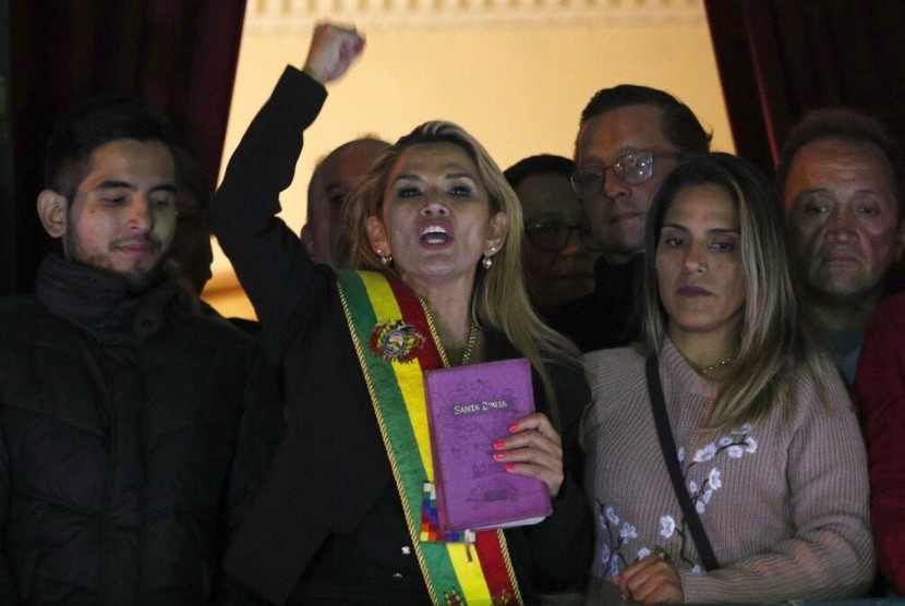 Wakil Presiden Kedua Bolivia dan politikus oposisi Jeanine Anez (tengah) sambil memegang Alkitab mendeklarasikan dirinya sebagai presiden sementara Bolivia dari atas balkon Istana Quemado di La Paz, Bolivia, Selasa (12/11).